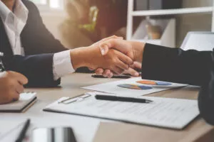 Image of two people shaking hands over a contract to augment the article which speaks to rent to buy South Africa